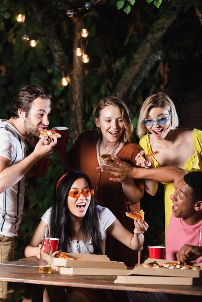 African american man pushing friends away from pizza near beer on table outdoors  - Foto, Imagem
