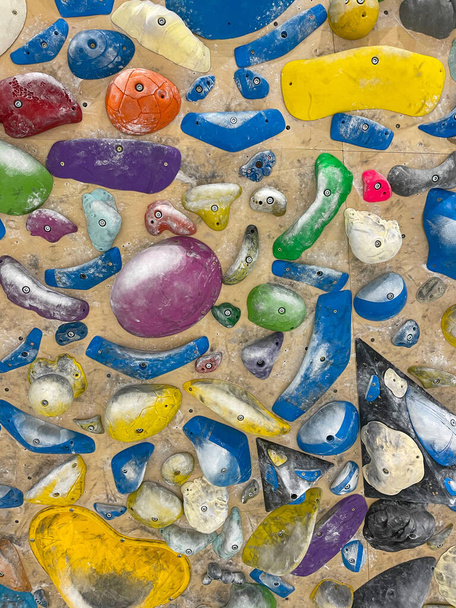 VERTICAL: Detailed shot of colorful grips covered in chalk at a bouldering gym. - Foto, Bild