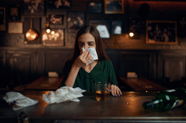 Drunk woman wipes her nose with a napkin in bar - Foto, immagini