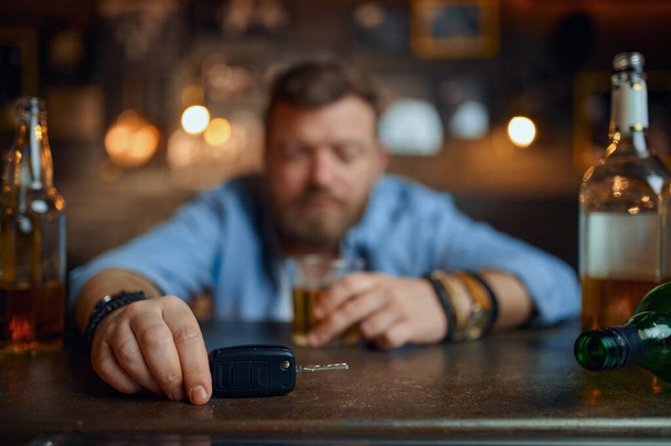 Μεθυσμένος άνδρας με κλειδί αυτοκινήτου κάθεται στον πάγκο στο μπαρ - Φωτογραφία, εικόνα