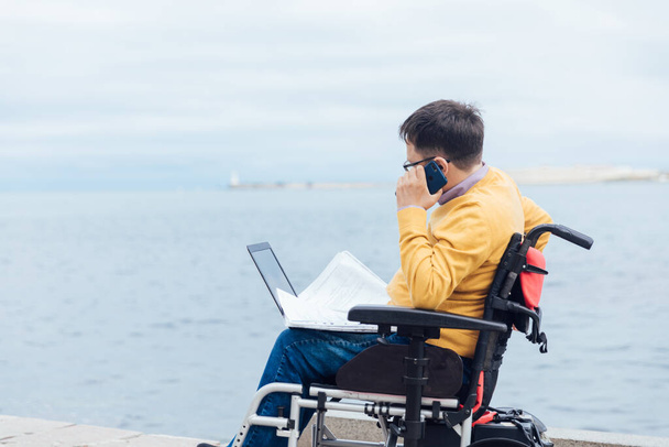 スマートフォンで話している車椅子の障害者が - 写真・画像