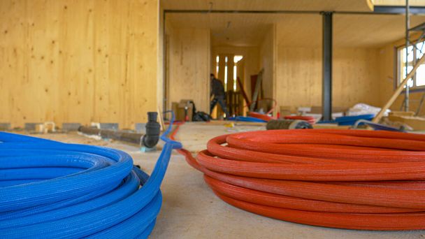 ÁNGULO BAJO: Las bobinas de mangueras de goma de colores yacen en el suelo de una obra de construcción. - Foto, imagen
