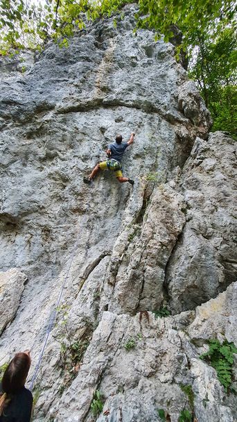 VERTICAL: Hombre atlético escalador de roca está siendo engañado por una mujer irreconocible. - Foto, imagen