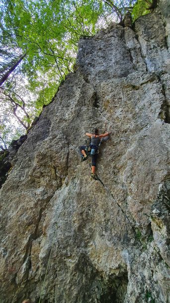 VERTICAL: Female rock climber scales a steep wall with top rope technique. - Photo, Image