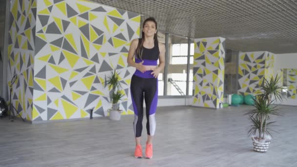 Ενεργειακή αθλητική γυναίκα τρέχει στη θέση του, δείχνει καρδιο ασκήσεις - Πλάνα, βίντεο