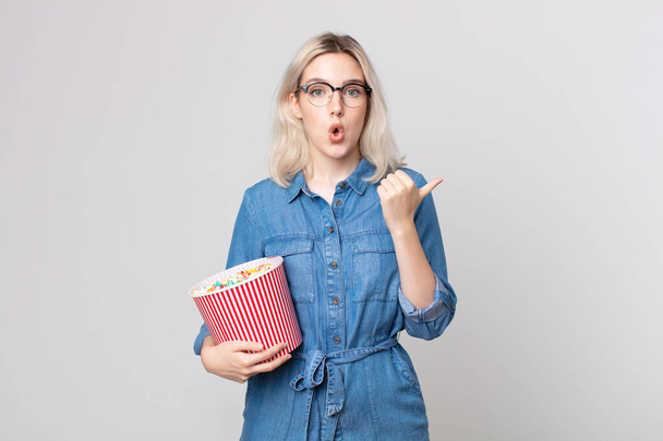 young pretty albino woman looking astonished in disbelief with a pop corns bucket - Photo, Image
