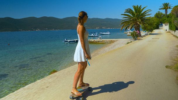 Turista femenina está montando elongboard mientras explora Peljesac durante sus vacaciones - Foto, imagen