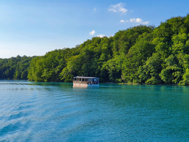 Croisières en bateau touristique le long du lac émeraude à Plitvice entouré d'une forêt luxuriante. - Photo, image