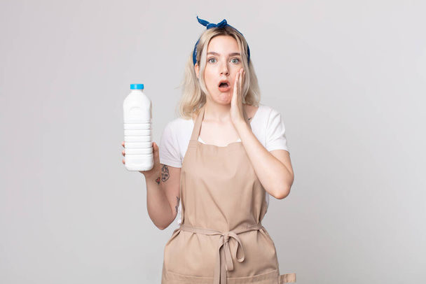 young pretty albino woman feeling shocked and scared with a bottle of milk - Photo, image
