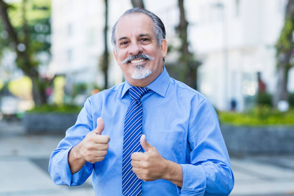 Laughing mexican senior businessman showing both thumbs up - Fotó, kép