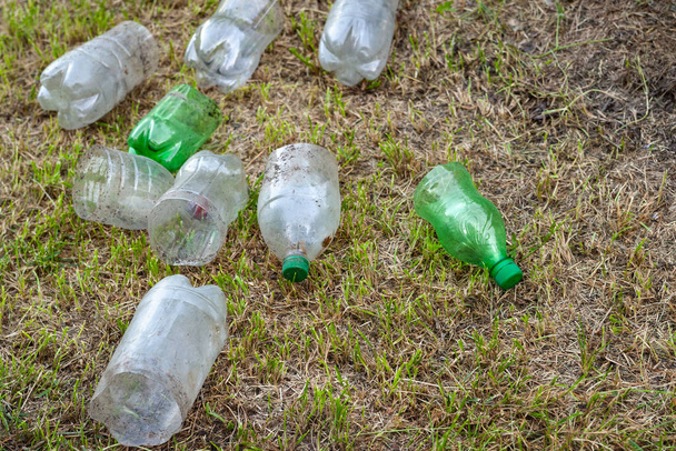 Plastikowe butelki. Stos zużytych starych brudnych plastikowych butelek leży na trawie, widok z góry. Koncepcja zanieczyszczenia środowiska. Problem ekologiczny. Recykling odpadów z tworzyw sztucznych. Selektywne miękkie skupienie. - Zdjęcie, obraz