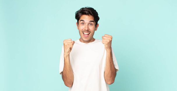 hispanic handsome man feeling shocked, excited and happy, laughing and celebrating success, saying wow! - 写真・画像