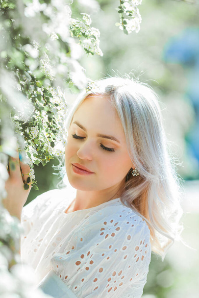 Portret van een jonge mooie vrouw in een bloeiende tuin. Voorjaar. - Foto, afbeelding