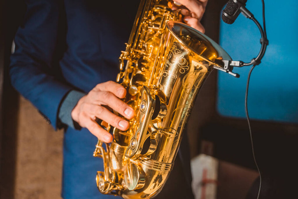 a man plays a saxophone with a microphone attached close up - Fotó, kép
