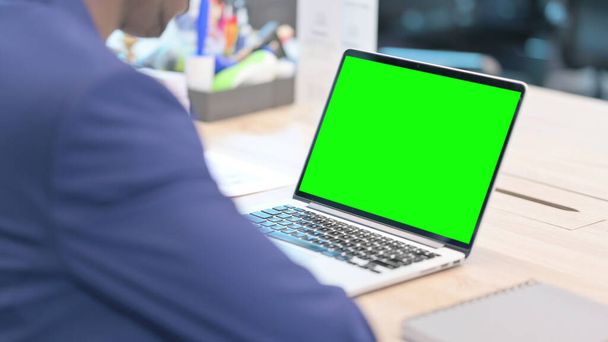Vista trasera del hombre de negocios utilizando el ordenador portátil con pantalla de croma - Foto, imagen