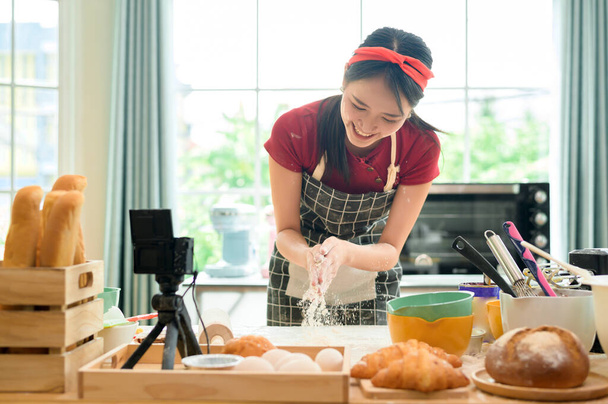 A Beautiful asian woman is making bakery ,   live streaming or recording video on social media in her house   - Фото, изображение