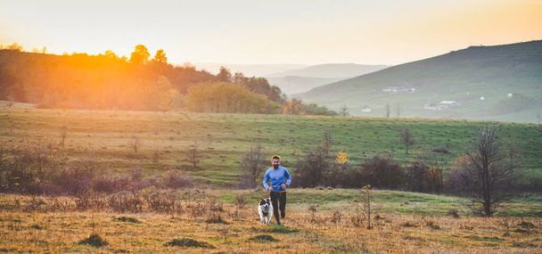 happy dog and man running in autumn field - Фото, зображення