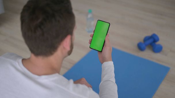 Young Man using Smartphone with Chroma Key Screen on Yoga Mat - Φωτογραφία, εικόνα