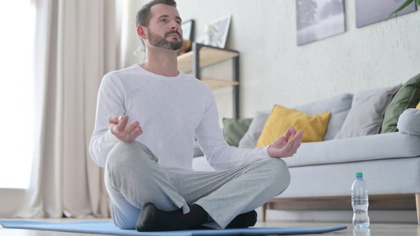 Крупним планом зрілий дорослий чоловік робить йогу вдома
 - Фото, зображення
