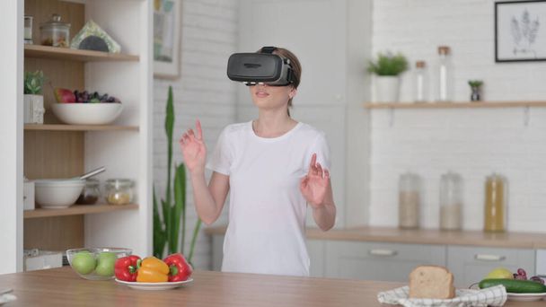 Modern Woman using VR Set while Standing in Kitchen  - Foto, afbeelding