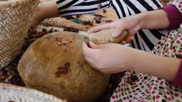 Μια Μαροκινή ανοίγει καρύδια Argan για να εξαγάγετε τους πυρήνες για την παραδοσιακή χειροποίητη παραγωγή λαδιού Argan. Το λάδι είναι πλούσιο σε λιπαρά οξέα και χρησιμοποιείται στη μαγειρική και στα καλλυντικά. - Πλάνα, βίντεο