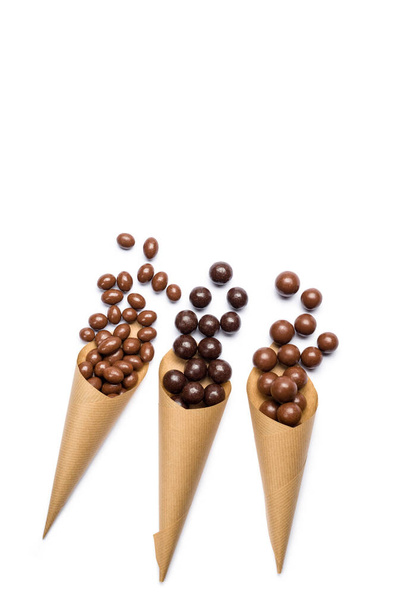Diverses saveurs de pralines au chocolat dans des cônes en papier sur fond blanc. - Photo, image