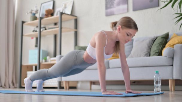 Egy nő fekvőtámaszt csinál a jóga matracon otthon - Fotó, kép