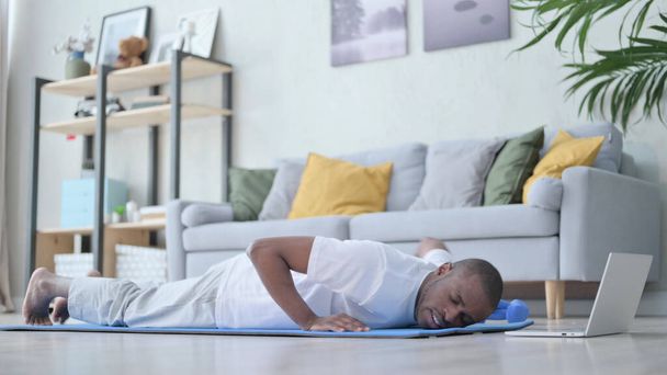 Zmęczony Afrykanin robi pompki na macie jogi w domu - Zdjęcie, obraz
