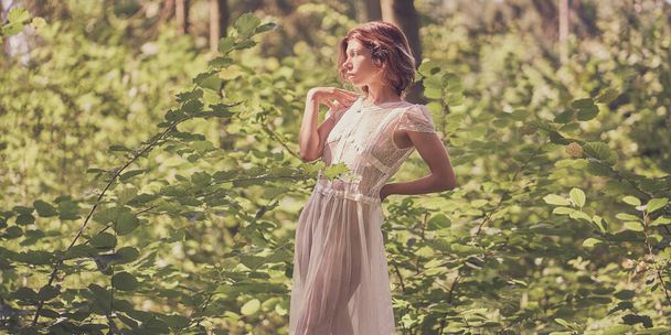          Girl in a lace dress on the background of bright foliage of the forest                       - Foto, imagen