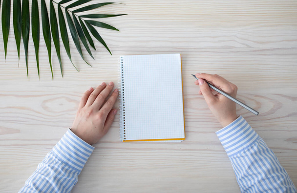 Confira lista e conceito de inspiração. Mãos femininas escrevendo em caderno vazio com espaço livre, segurando lápis, vista superior - Foto, Imagem