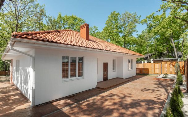 Kerti modern fehér vidéki ház barna tetővel.  - Fotó, kép