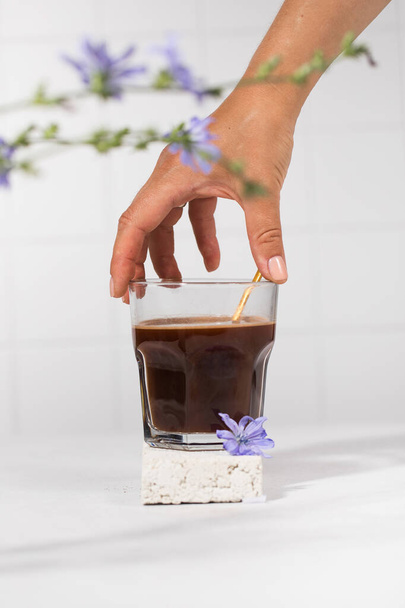 Chicory drink in a transparent mug with chicory flowers in the foreground. - 写真・画像