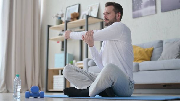 Mature homme adulte faisant des étirements sur tapis de yoga à la maison - Photo, image