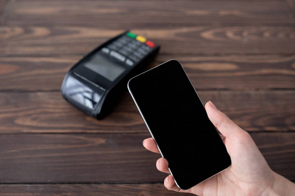 Lady bezahlt kontaktlos per Smartphone mit moderner easy nfc-Technologie, hält Handy mit leerem schwarzen Bildschirm - Foto, Bild