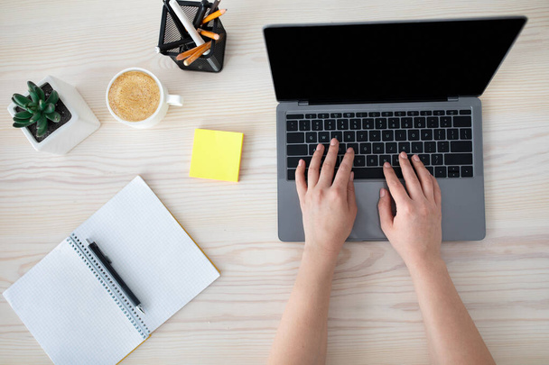 Miejsce pracy. Kobieta wpisująca na laptopie klawiaturę i notatki do pisania, siedząca przy biurku, widok z góry, makieta, przestrzeń do kopiowania - Zdjęcie, obraz