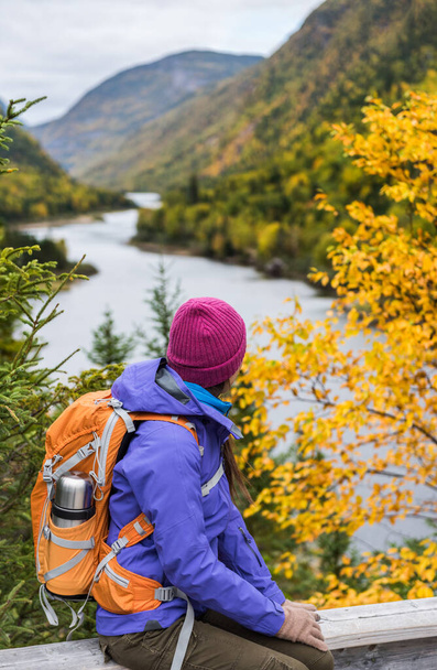 Woman hiker hiking looking at scenic view of fall foliage mountain landscape . Adventure travel outdoors person standing relaxing near river during nature hike in autumn season. - Photo, Image