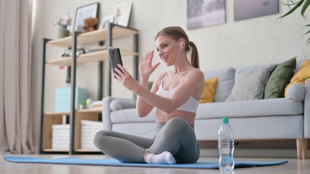 Mujer hablando en videollamada en Smartphone mientras está sentada en Yoga Mat  - Foto, imagen