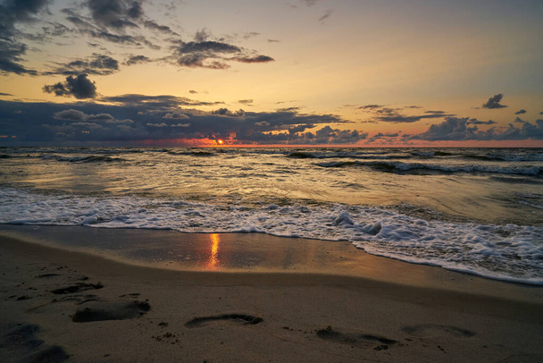 嵐の後の海岸の上の壮大な暗い日没の空.  - 写真・画像