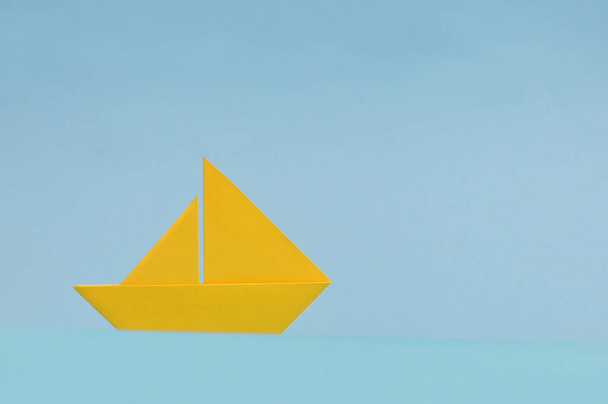 Conceptual Yellow Paper boat On Blue Background - 写真・画像