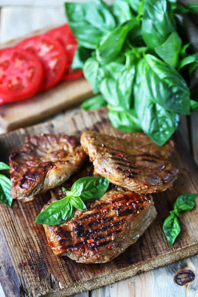 Grilled juicy steaks on a wooden surface. Steak house menu. - Photo, Image