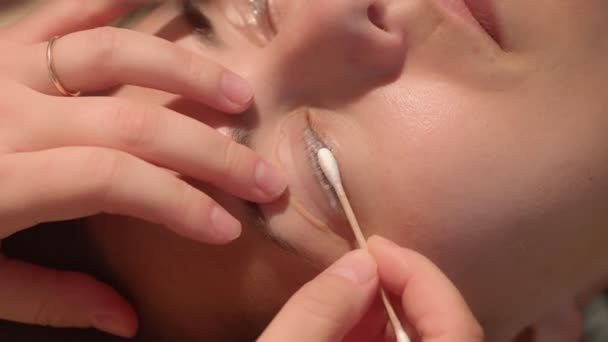 Estetista pulizia ciglia oculari di una giovane signora caucasica durante la procedura di laminazione. Video di alta qualità di primo piano estremo. - Filmati, video
