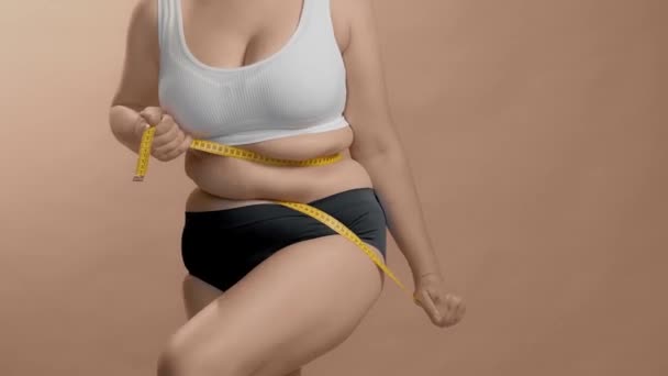 Mulher caucasiana excesso de peso com fita métrica enrolada em torno de sua cintura. Ainda filmado vídeo de alta qualidade. - Filmagem, Vídeo