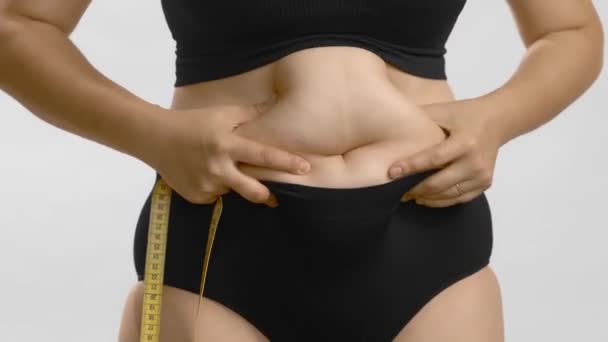 Turbato plus size donna spremendo l'addome e cercando di succhiare nello stomaco. Video di studio di alta qualità. - Filmati, video