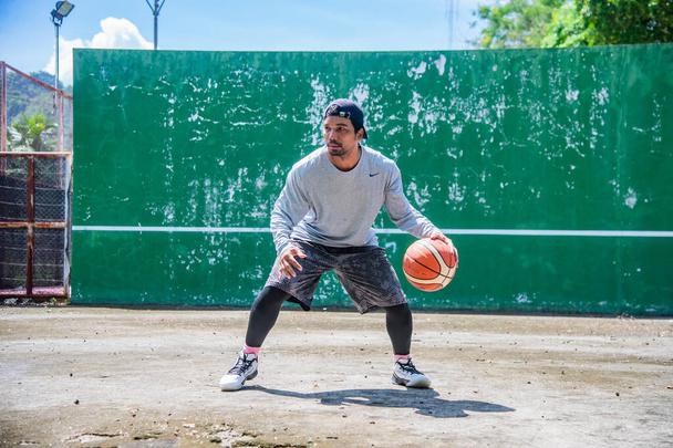 Uomo che si allena all'aperto al sole giocando a basket durante la crisi del COVID-19, 26 giugno 2021, Surat Thani, Thailandia. - Foto, immagini
