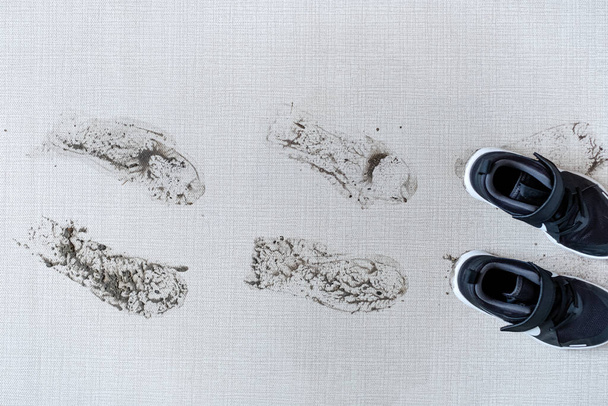 Vuile schoenen die modderige voetafdrukken achterlaten op tapijt. Bovenaanzicht. Hoge kwaliteit foto - Foto, afbeelding