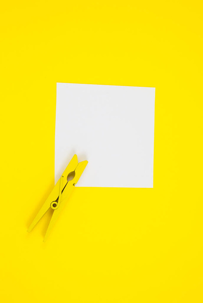 Blank white To Do List Sticker with yellow wooden clothespin. Close up of reminder note paper on the yellow background. Copy space. Minimalism, original and creative photo. - Фото, изображение