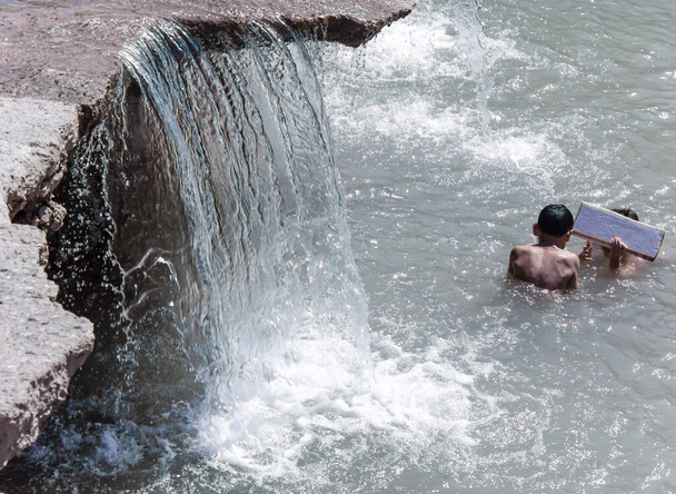 Τα παιδιά κάνουν μπάνιο στα ρυάκια του ποταμού. Ανθυγιεινές συνθήκες. - Φωτογραφία, εικόνα