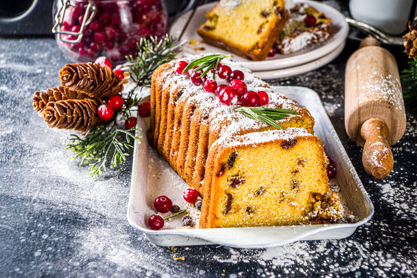 Tradiční vánoční pečení, slavnostní vánoční ovocný dort se sušeným ovocem, likérem a brusinkovou výzdobou. Domácí ovocný koláč na vánoční zdobené pozadí - Fotografie, Obrázek