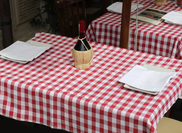 piros-fehér kockás abroszok egy üveg vörösborral az olasz trattoriában - Fotó, kép