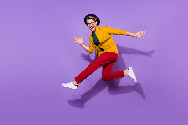 Teljes test profil oldal fotó a fiatal férfi boldog pozitív mosoly ugrás fuss gyorsan elszigetelt lila szín háttér - Fotó, kép